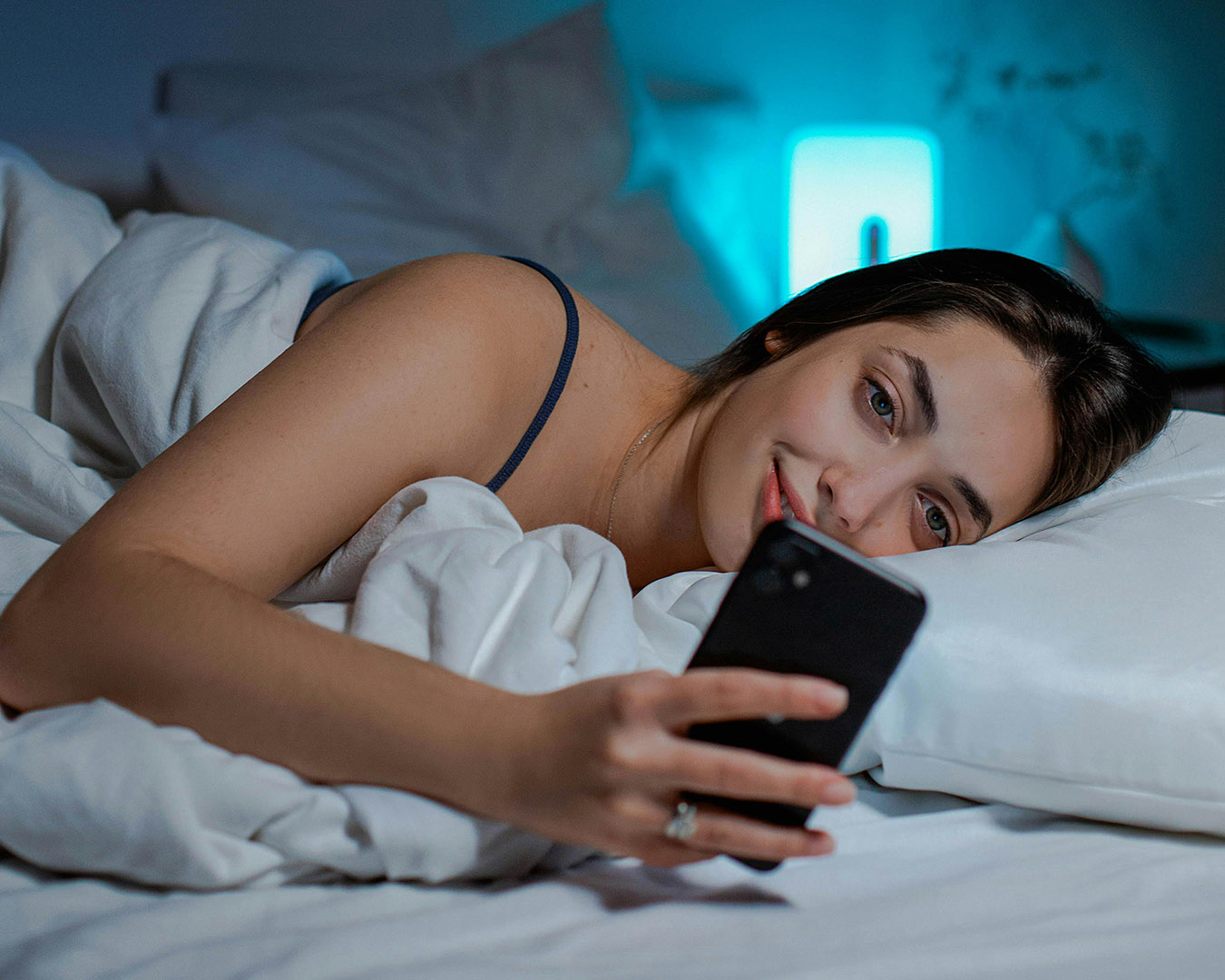 A Woman Using Her iPhone while Lying in Bed